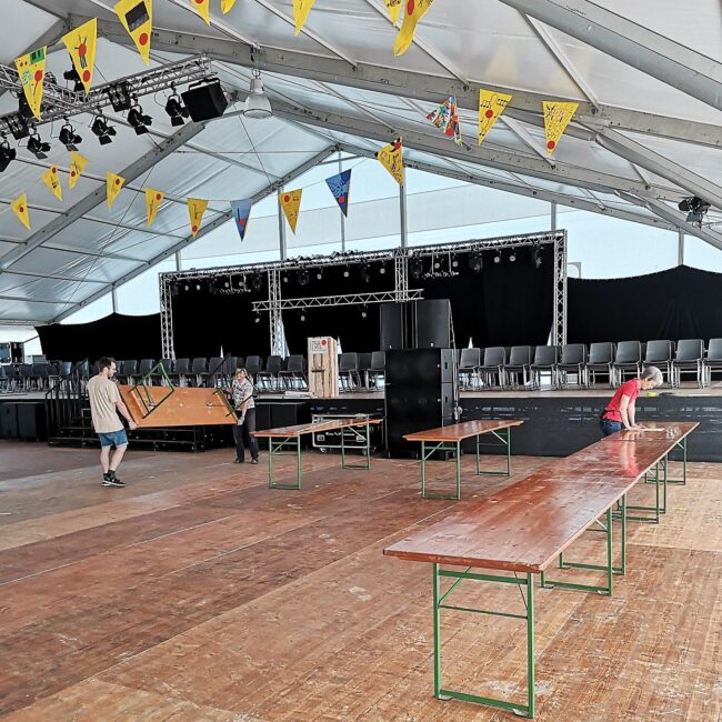 Die Fähnlein sind aufgehängt, die Stühle stehen auf der Bühne und die Festgarnituren werden im Festzelt für den Musiktag Ruswil aufgestellt.